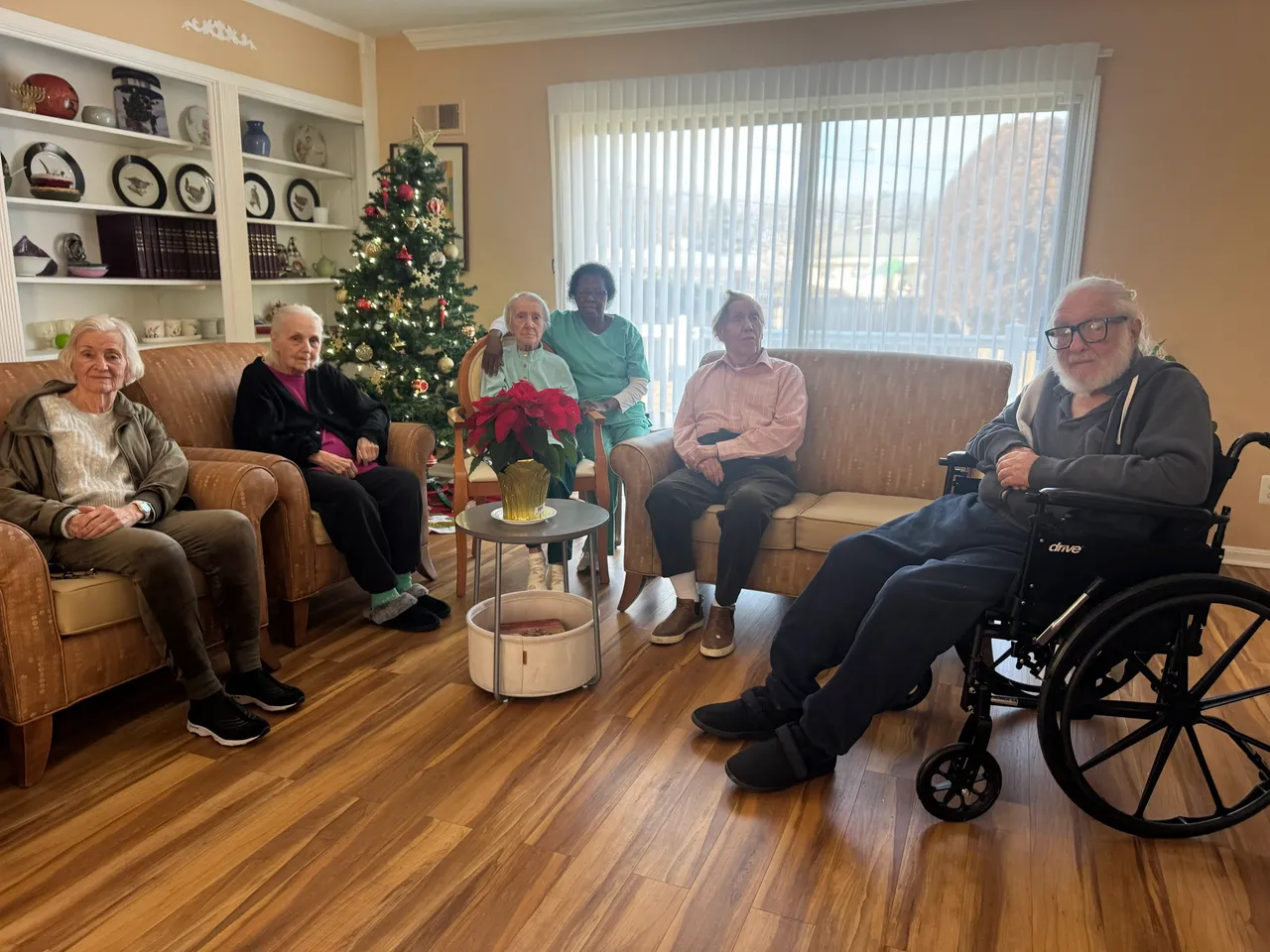 Residents and caregiver gathered by the Christmas tree